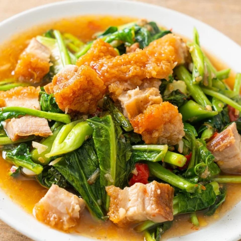 Crispy pork belly stir-fried with vibrant green kale in a savory sauce, a Thai Del Mar specialty.